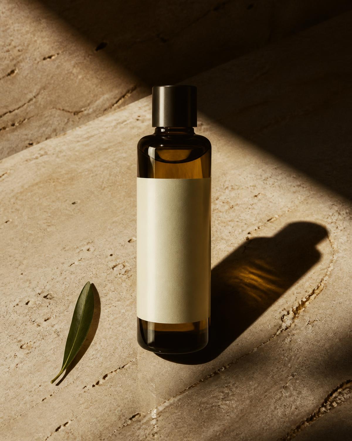 Amber glass bottle of Lispa signature oil on travertine in hard sunlight